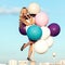 Happy young woman with colorful latex balloons