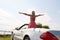 Happy young woman in convertible car at seaside