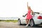 Happy young woman in convertible car waving hand