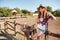 Happy young woman cowgirl with cell phone showing peace sign