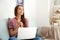 Happy young woman with credit card and laptop after online shopping at home