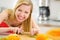 Happy young woman cutting fruits in kitchen
