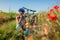 Happy young woman cyclist taking her helmet off after riding bicycle in summer poppy field. Having rest after workout