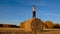 Happy young woman, dancing on haystacks. Pretty girl in casual clothes gets fun on farmer field