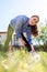 A happy young woman is doing sports in the yard, doing bends to her feet. View from below, from the grass. Concept of outdoor