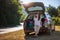 Happy young woman driver traveler in sunglasses  sitting in open car trunk. Road trips and summer holidays