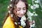 Happy young woman enjoying smell flowers over spring garden background