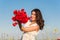 Happy young woman in the field with a poppies bouquet.