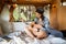 Happy young woman with guitar relaxing on bed inside mobile house