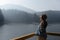 Happy young woman in hat enjoys lake view in mountains . Relaxing moments in forest. Freedom, people, lifestyle, travel