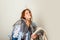 Happy young woman holding bunch of messy seasonal clothes on white background.