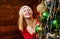 Happy young woman holding Christmas bauble in front of Christmas tree. Beauty girl decorating Christmas tree. Girl is