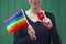 Happy young woman holding lgbt colorful rainbow flag and red wooden heart