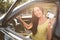 Happy young woman holding license while sitting in car outdoors. Driving school