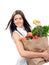 Happy young woman holding a shopping bag full of groceries fruit