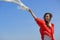 Happy young woman holding white scarf with opened arms expressing freedom, outdoor shot against blue sky