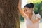 Happy young woman lean against tree