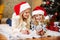 Happy young woman and little girl in Santa`s hat playing with sn