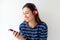 Happy young woman looking at mobile phone and listening to music with headphones