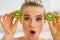 Happy young woman making eyes with kiwi slices