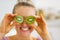 Happy young woman making eyes with kiwi slices