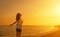 Happy young woman open her arms to the sky and sea at sunset