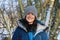 Happy young woman outdoors wearing cold weather clothing in snowy woodland.