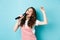 Happy young woman perform song, singer holding microphone, dancing and singing at karaoke, standing over blue background