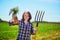 Happy young woman with pitchfork and ripe organic carrots