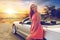 Happy young woman posing at convertible car