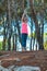 Happy young woman practicing yoga with hands raised up into the woods outdoors. Upward Salute pose