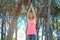 Happy young woman practicing yoga with hands raised up into the woods outdoors. Upward Salute pose