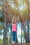 Happy young woman practicing yoga with hands raised up into the woods outdoors. Upward Salute pose