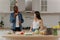 A happy young woman prepares a salad in the kitchen, a handsome man juggles tomatoes nearby. A couple in the kitchen