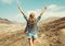 Happy young woman raises hands up on a hiking trail on top of the mountain, view from the back, Tenerife, Canary Islands