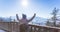 Happy young woman is raising her hands on the mountain, enjoying the view over Salzburg. Winter time on Gaisberg, Salzburg,