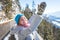 Happy young woman is raising her hands on the mountain, enjoying the view over Salzburg. Winter time on Gaisberg, Salzburg,