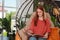 Happy young woman reading magazine in egg chair at indoor terrace