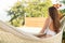 Happy young woman relaxed lies in a hammock on the balcony House. Woman basks and sunbathes in a hammock