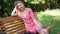 Happy young woman resting on bench in park