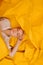 Happy young woman with short hair lying on her back on yellow cramped paper