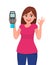 Happy young woman showing/holding pos payment terminal or credit/debit cards swiping machine, gesturing okay/OK sign.