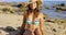 Happy young woman sitting on beach sand