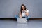 Happy young woman sitting on the floor with crossed legs and using laptop on gray background.