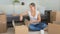 Happy young woman sitting on the floor and unpacking cardboard boxes with things