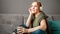 Happy young woman sitting on sofa with in headphones with cup of tea. Woman or teen girl resting, bliss enjoy listening to music