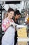 Happy Young Woman Slicing Cheese With Knife In Shop