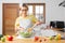 happy young woman smiling preparing vegetable salad in the kitchen