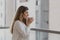 Happy young woman sniffs cup of tea or coffee with blurred city background.