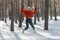 Happy young woman in snowy forest jumps high. Walk through the winter wood on sunny day